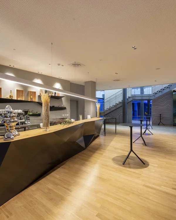 Modern space with wooden counter and tall tables on light floor