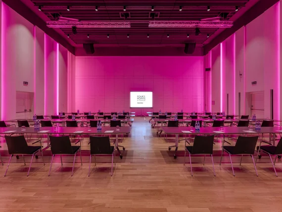 Sala conferenze con illuminazione rosa e sedie disposte attorno a tavoli