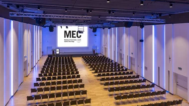 Sala conferenze moderna con sedie disposte in file e grande schermo MEC