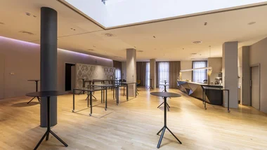 Sala moderna con tavoli alti neri e pavimento in legno chiaro