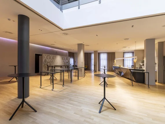 Sala moderna con tavoli alti neri e pavimento in legno chiaro