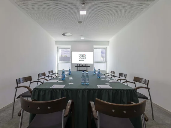 Sala conferenze con tavolo, sedie, bottiglie d'acqua e schermo con logo Four Points