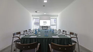 Sala conferenze con tavolo, sedie, bottiglie d'acqua e schermo con logo Four Points