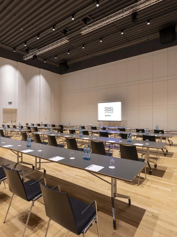 Sala conferenze con tavoli, sedie, acqua e blocchi per appunti