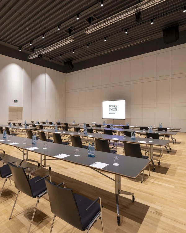 Konferenzraum mit Tischen, Stühlen, Wasserflaschen und Notizblöcken