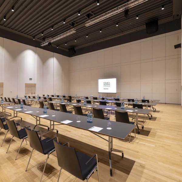 Sala conferenze con tavoli, sedie, acqua e blocchi per appunti