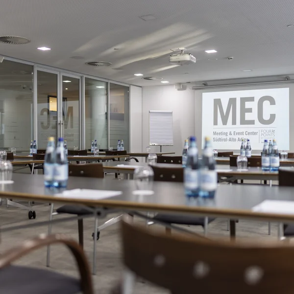 Sala conferenze con tavoli, sedie e bottiglie d'acqua pronte per un evento