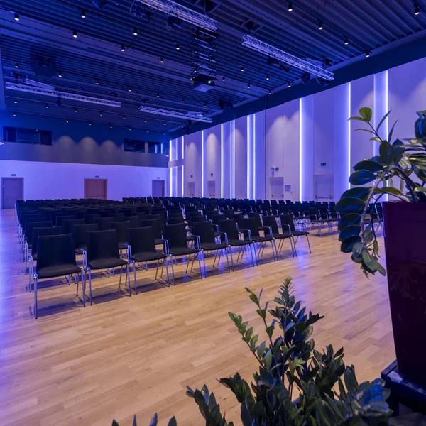 Sala conferenze moderna con sedie nere e illuminazione blu